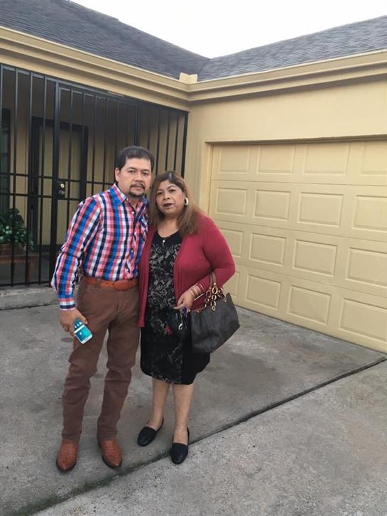 Two individuals stand close together outside a garage, smiling and enjoying their time.