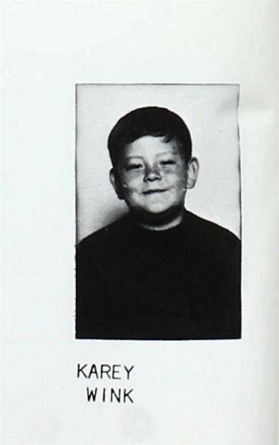 A joyful young boy with a warm smile poses in a casual outfit, suggesting a school environment.
