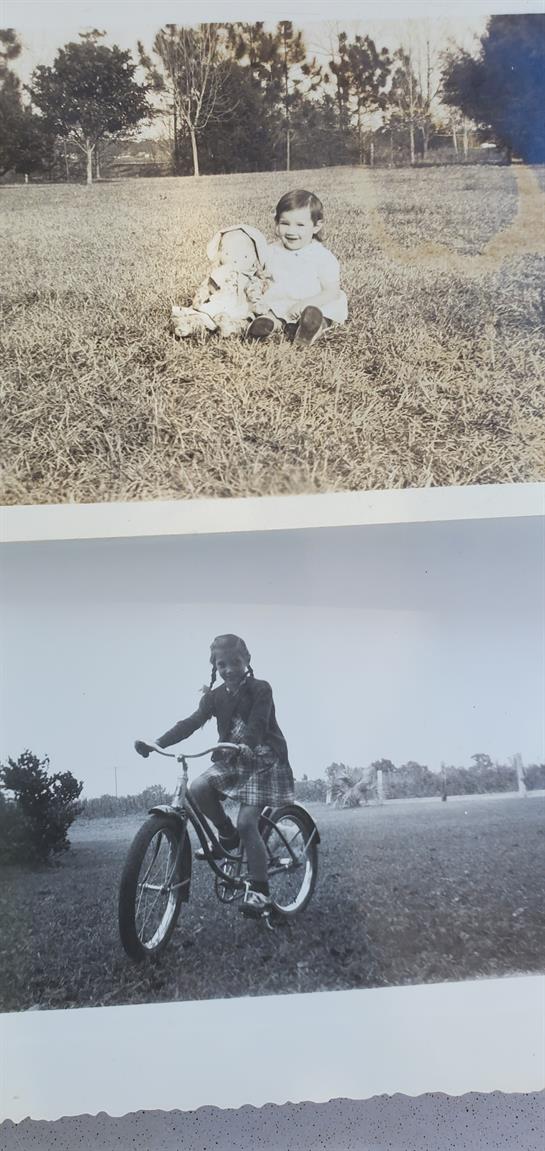 A child enjoys a bike ride on a grassy field while a dog rests nearby under the sun.