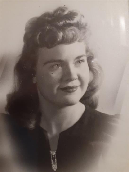 A smiling young woman in a black top captures a timeless moment with her wavy hair.