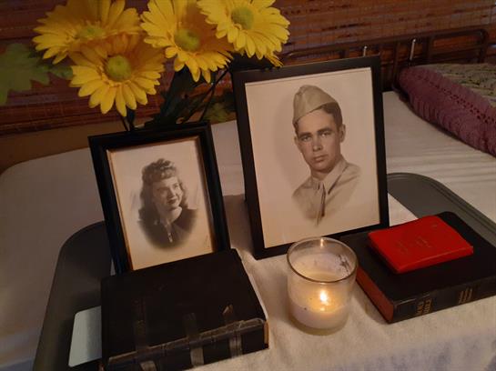 Vintage portraits of a military man and a woman are displayed with flowers and a candle.