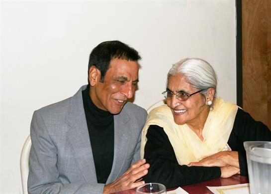 Two people laugh and enjoy each other's company at a small gathering.