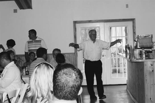 An elderly man showcases his dance skills at a community gathering, entertaining the audience.
