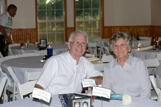 Couple smiles as they sit together at a beautifully arranged table during a local event.