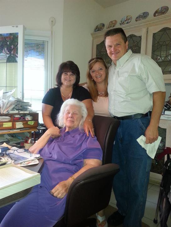 Four family members share joyful moments in a sunlit living room with an elderly woman.