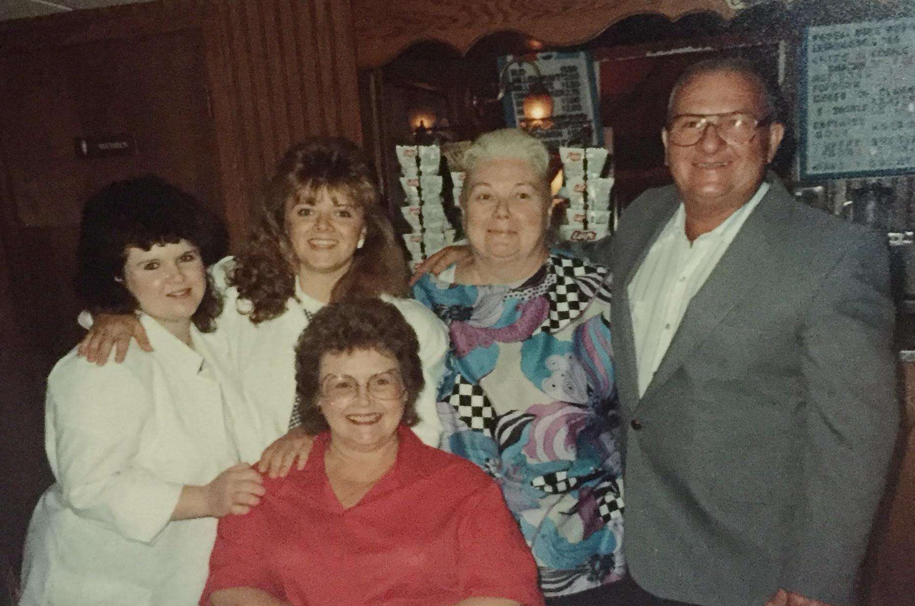 Friends are gathered at a restaurant, sharing smiles and enjoying each other's company at night.