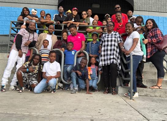 A large group of individuals stands together outside a community venue, celebrating friendship.