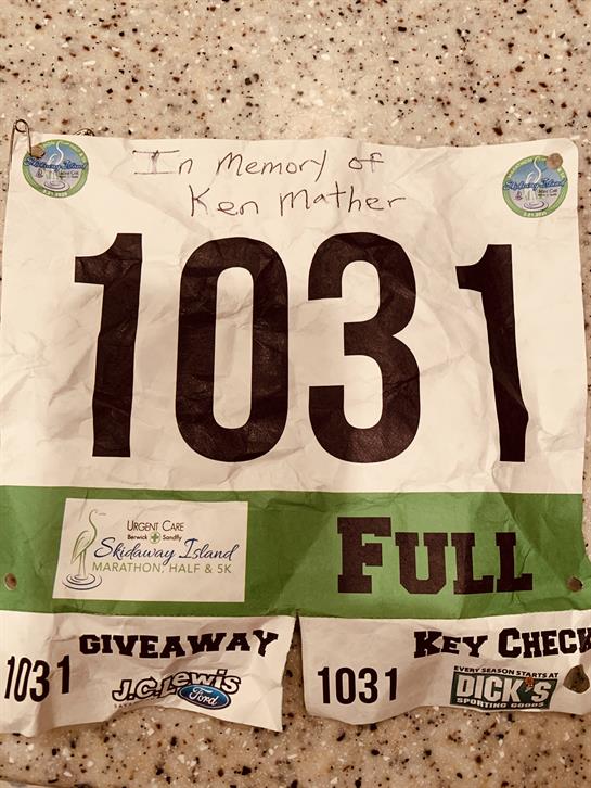Displayed is a worn race bib with the number 1031, honoring Ken Mather during a marathon.