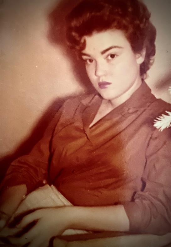 A young woman in classic attire sits elegantly, her expression thoughtful and serene.