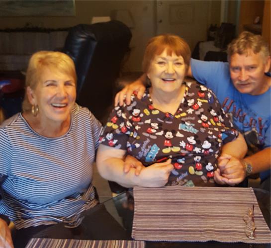 Three friends smile and enjoy each other's company while seated at a table with vibrant decor.