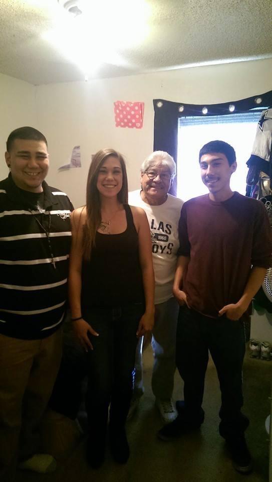 Four friends stand together, smiling warmly in a colorful, lively room.