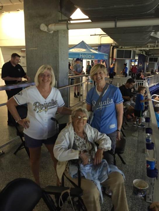 Three friends, including an elderly woman, gather together at a baseball game, enjoying the event.