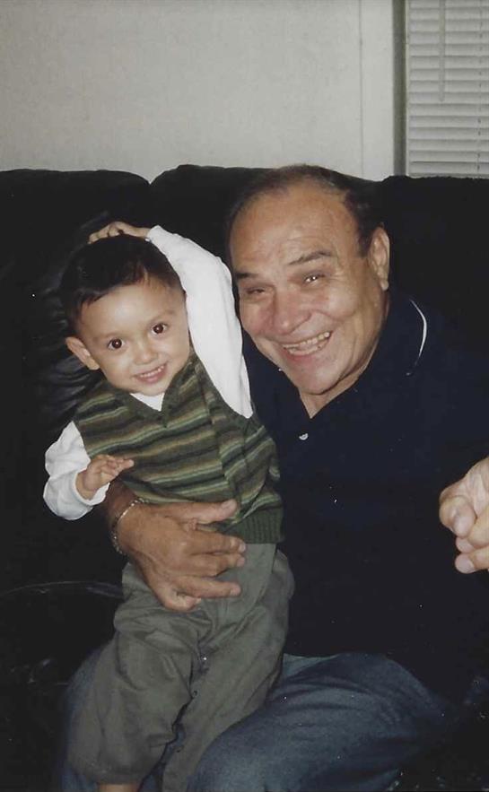 Grandfather and grandson share joyful laughter while playing together on a couch.