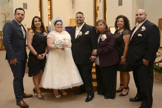 A couple in formal wear celebrates their wedding day surrounded by family and friends in a church.