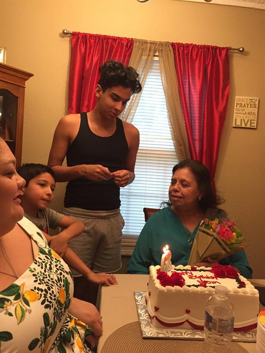 Family gathers around a decorated cake, enjoying laughter during a birthday celebration.