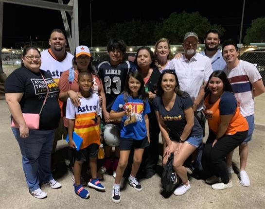 Group of people enjoying a lively night at a local sports event, celebrating together and smiling.