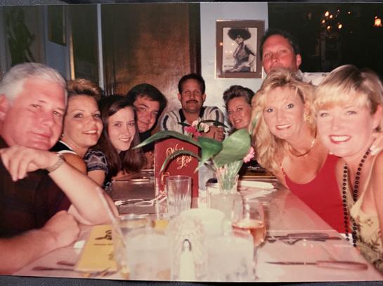 Friends gather around a table, sharing food and laughter at an informal dinner in the evening.