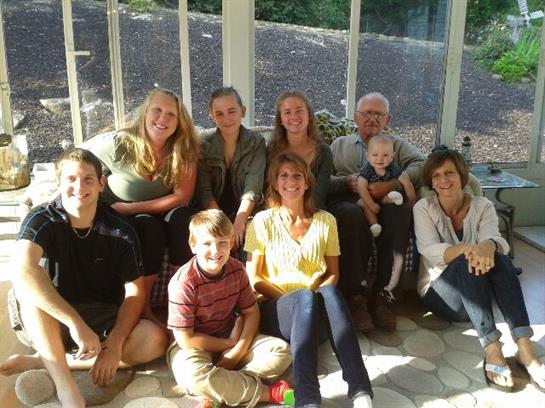 A family gathers in a bright room, smiling and enjoying time together.