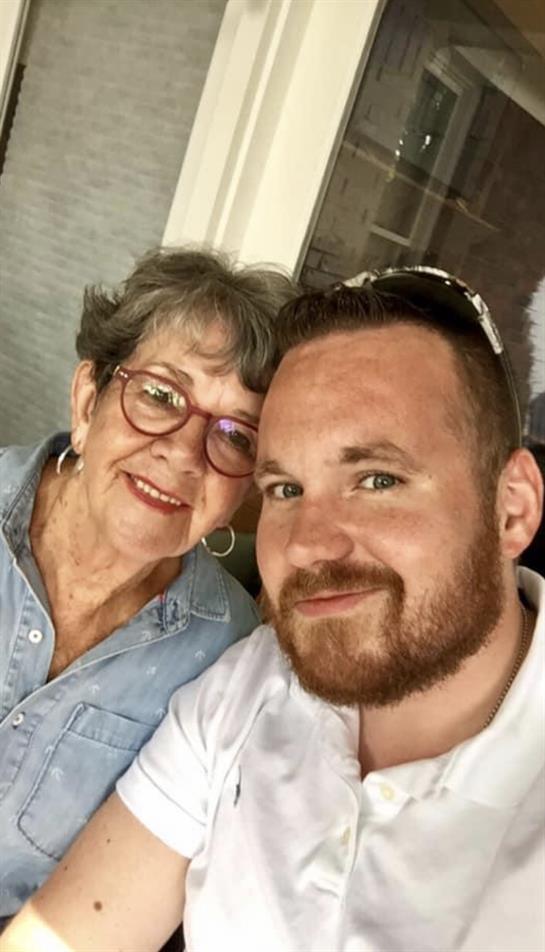A grandmother and grandson smile joyfully at each other in a relaxed environment with bright light.
