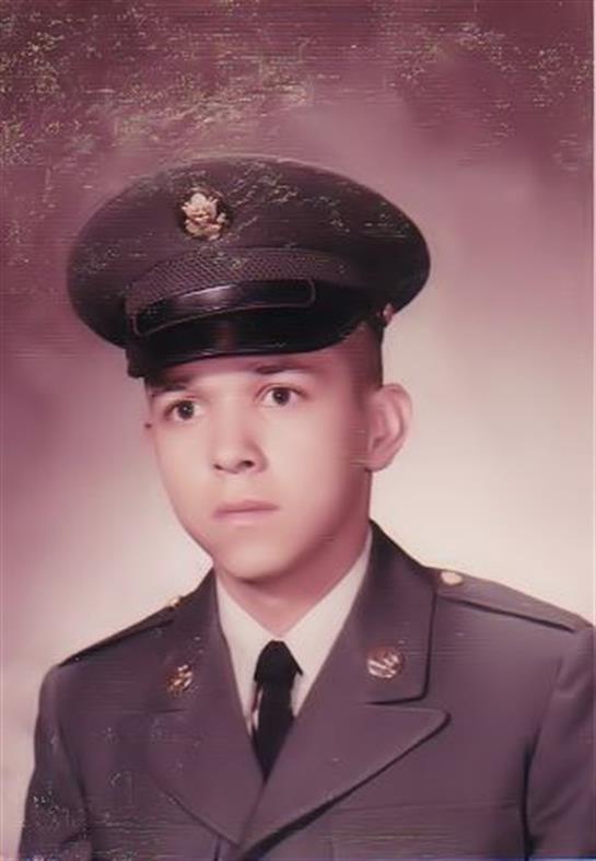 A young soldier in uniform stands straight, looking serious for a studio portrait.