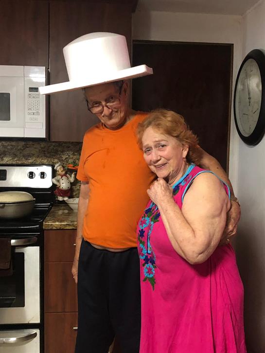 Joyful elderly couple shares a playful moment in their kitchen while cooking together.