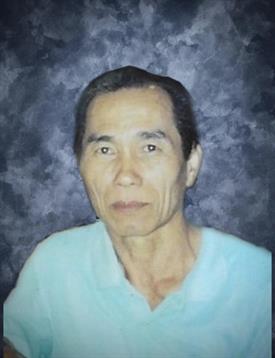 Senior individual with a calm expression stands facing the camera, showcasing a modest demeanor.