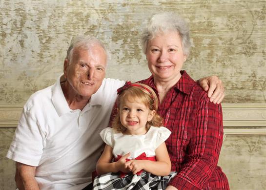 Grandparents pose with their cheerful granddaughter, creating a warm and loving atmosphere.