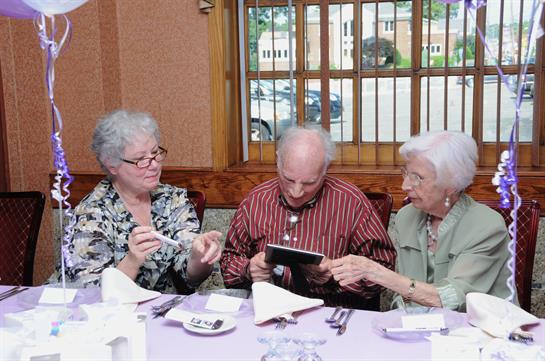 Three seniors gather around a table, sharing stories and laughter during a meal together.