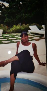 A woman relaxes outdoors in a beautiful garden, dressed casually.