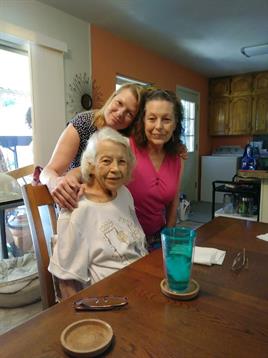 Three family members share smiles and laughter at the dining table in a cozy home setting.
