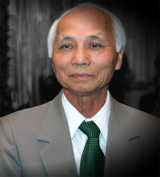 Elderly man smiles while dressed in a suit and green tie at an elegant gathering, exuding grace.