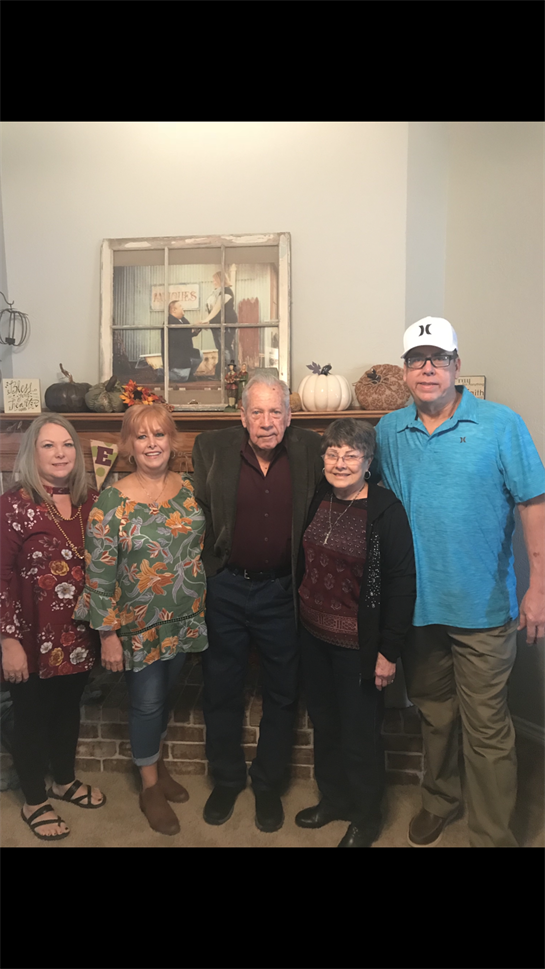 Family members pose together in a warm, decorated living room for a joyful autumn get-together.