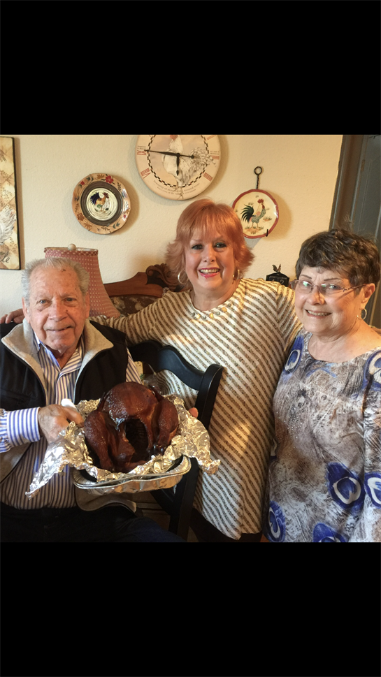Three family members proudly pose with a roasted turkey in a cozy kitchen setting.