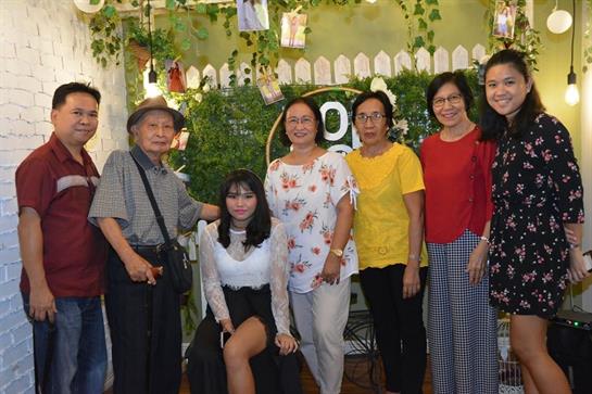 A joyful moment shared by family members in a lively cafe adorned with greenery.