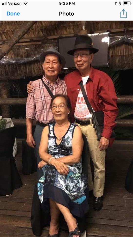 Three friends pose happily together, enjoying their time at a cheerful social event outdoors.