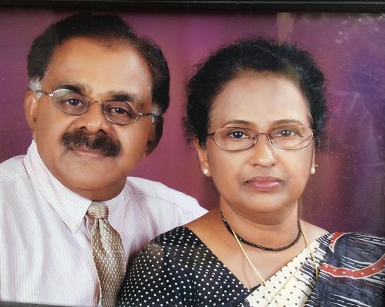 Couple wearing formal clothing and smiling together in a studio with a vibrant background.