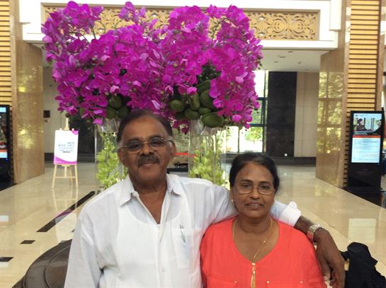 A couple smiles in a chic lobby decorated with lush purple flowers.