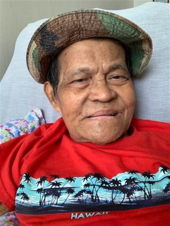 A man with a warm smile dressed in a red shirt and hat enjoys his time at home.