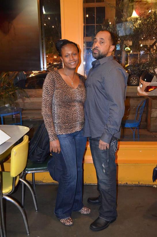 A couple stands close in a lively restaurant, enjoying their time together at night.