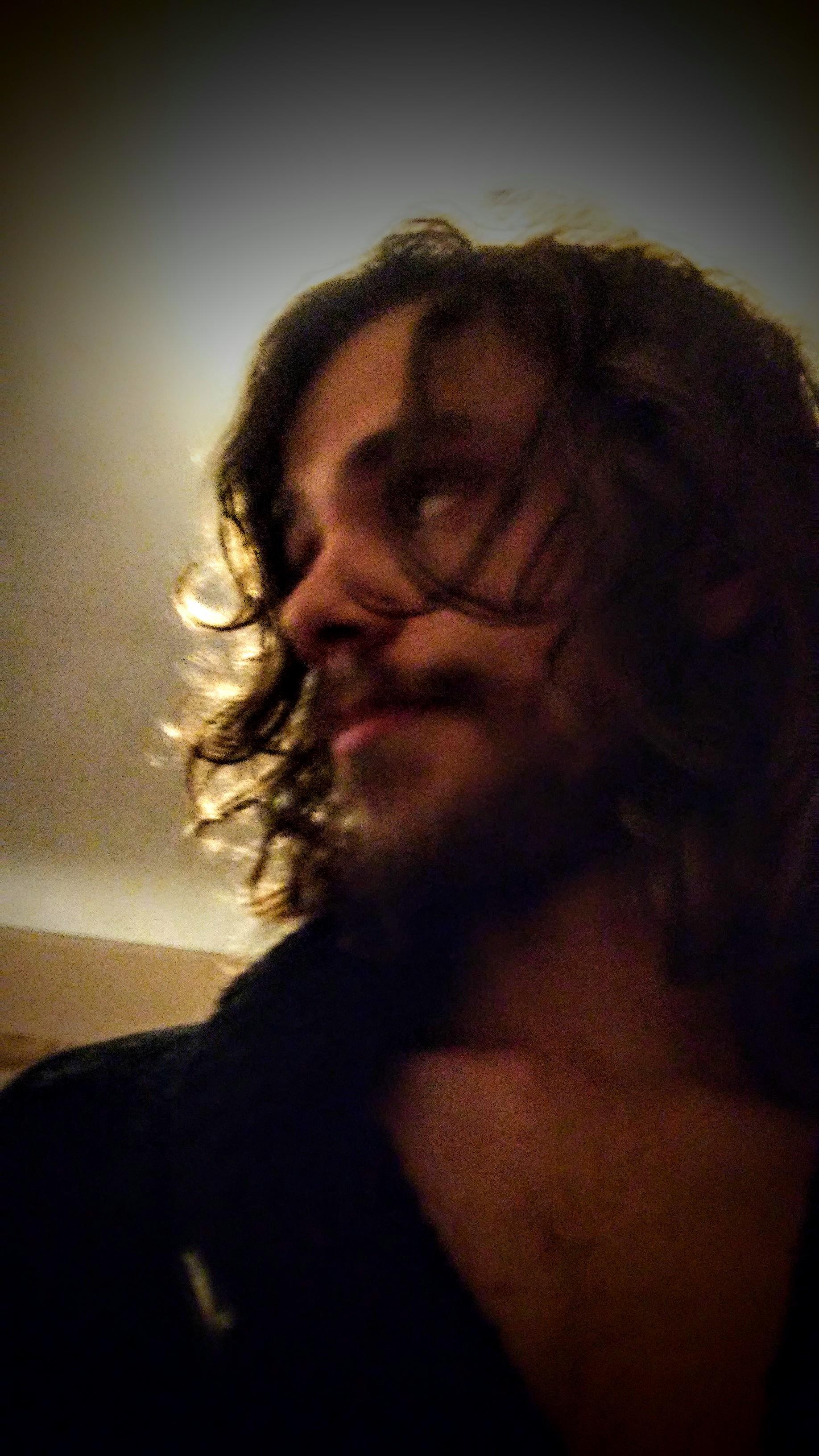 Curly-haired individual turns to look away, creating a relaxed and contemplative mood indoors.