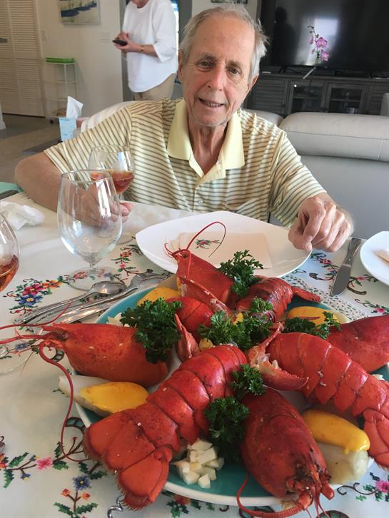 A man enjoys a vibrant lobster dish at a family dinner with drinks, showcasing festive vibes.