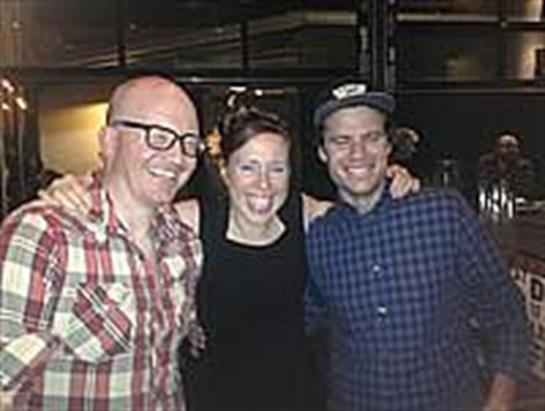 Three friends are joyfully posing together at an exciting event in a cozy location.