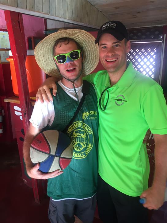 Two friends smile and pose with a basketball, enjoying a lively summer festival atmosphere.