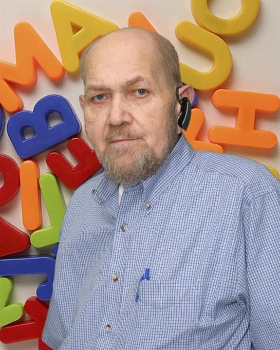 Elderly man smiles against a colorful letter background, embracing education.