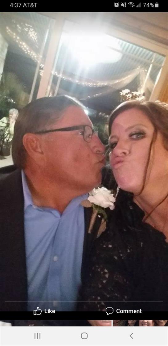 A couple enjoys a lighthearted moment, sharing a playful kiss at a wedding.