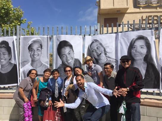 Participants joyfully gather in front of vibrant portraits showcasing diverse smiles.