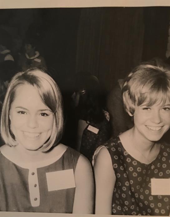 Two girls with stylish hairstyles are smiling happily, enjoying an event together.