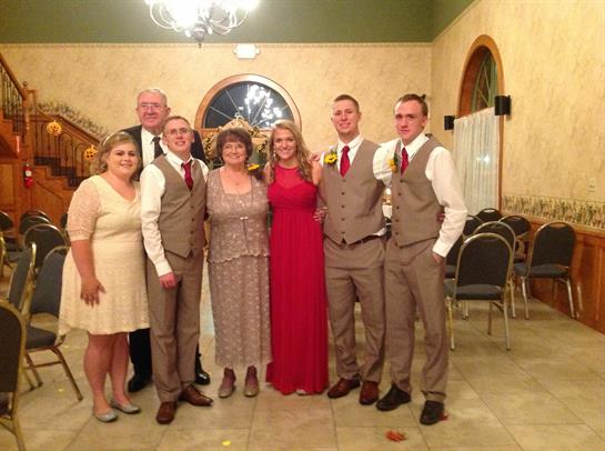 Family members pose together in formal attire, smiling and celebrating a special occasion.