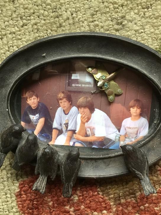Four boys appear relaxed in a vintage frame, capturing a playful memory in a warm, homey setting.
