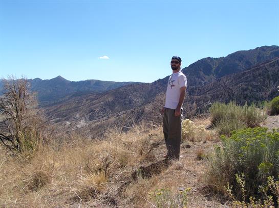 A person enjoys the stunning view from a mountain ridge on a sunny day in nature.